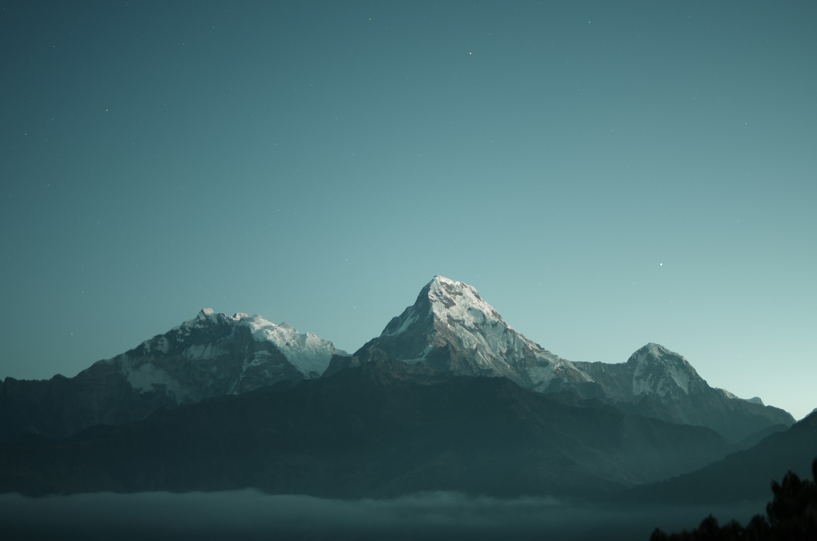 A coastal mountain range under a teal evening sky