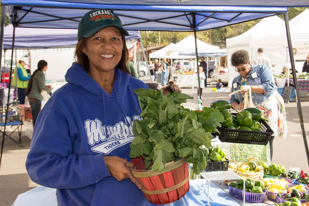 A trader holding a basket of greens at the market