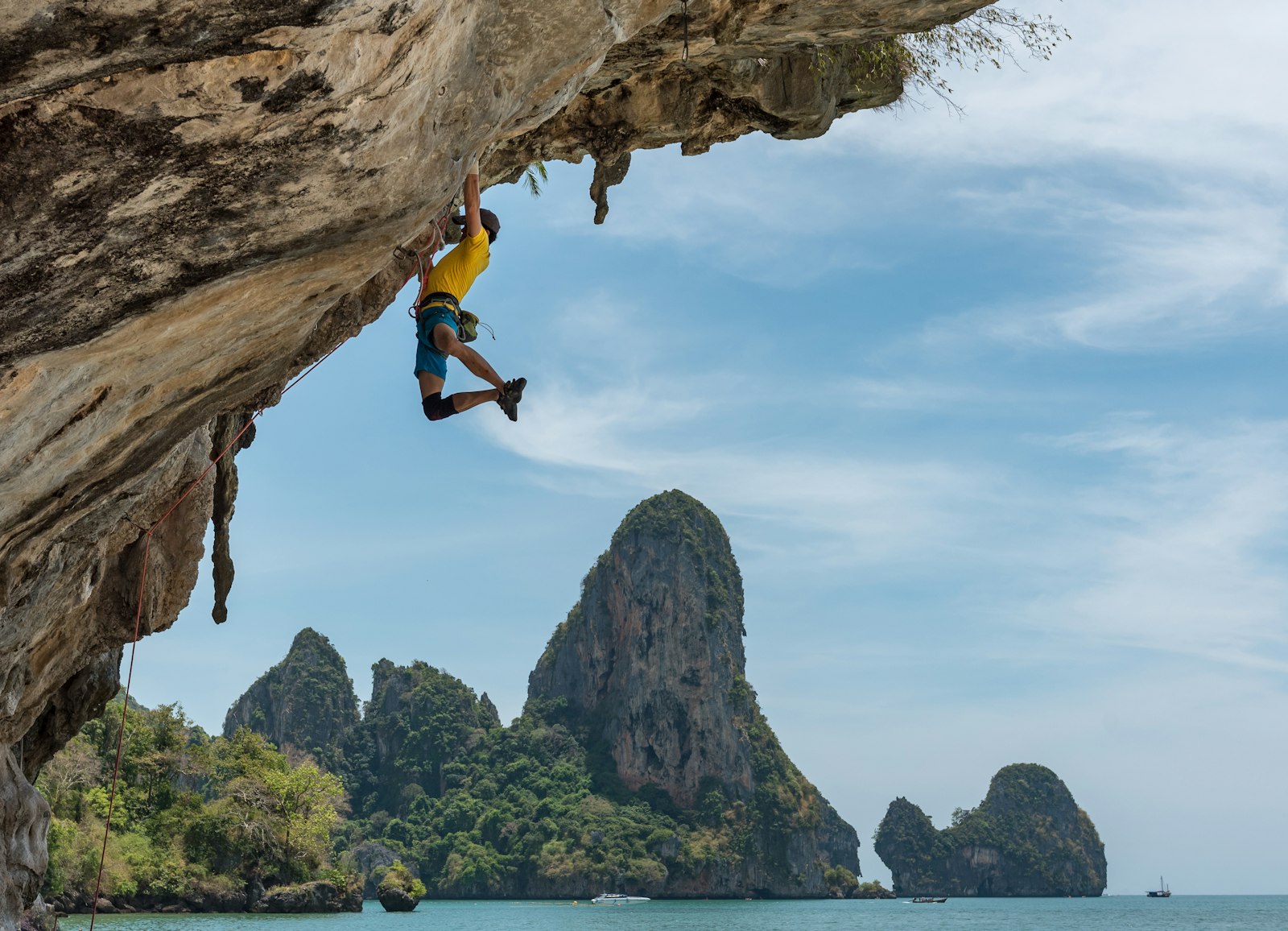 A climber mid move on a steep overhanging wall