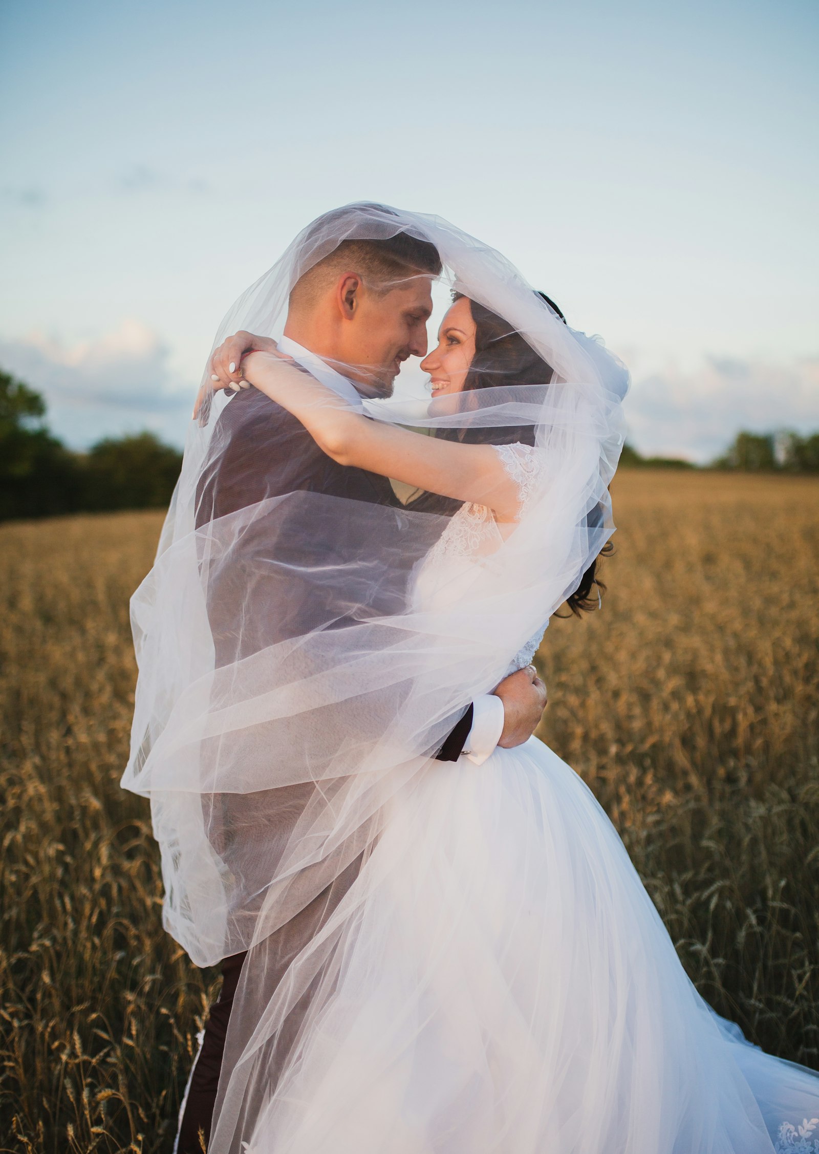 Couple under the veil in a field